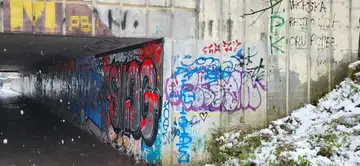 Z grafiti prekriti zidovi peš podhoda z nekaj snega na tleh