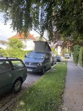 Kombi z dvignjeno streho parkiran ob pločniku in drevesih