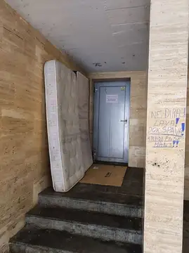 Vzmetnica in karton v stopnišču ob vratih z grafiti