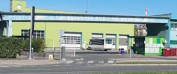 Avtobusno postajališče s postajališčem in koši za smeti ob zeleni stavbi