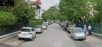 Ulica z veliko avtomobili parkiranimi na obeh straneh, nekateri ovirajo cesto