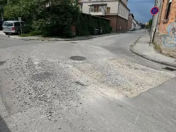 Poškodovana cesta z razsutim peskom na križišču