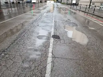 Mokra cesta z več luknjami in razpokami po dežju