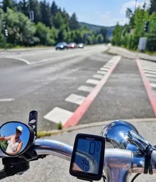 Krmilo kolesa z ogledalom in števcem ob cesti z rdečimi robnimi oznakami