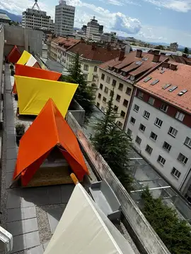Pisane tende na strešni terasi z mestnimi stavbami v ozadju