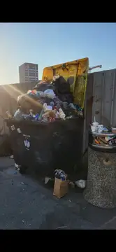 Prepoln koš za smeti z raztresenimi odpadki na cesti