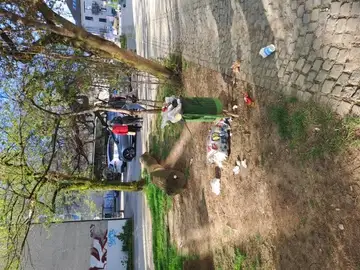 Prepoln koš za smeti z odpadki na tleh ob pločniku