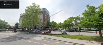 Parkirišče z avtomobili in drevesi ob večnadstropni stavbi