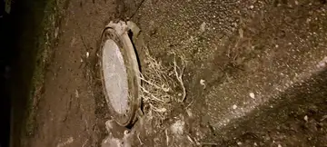 Udrt pokrov jaška s poškodovanim pločnikom okoli