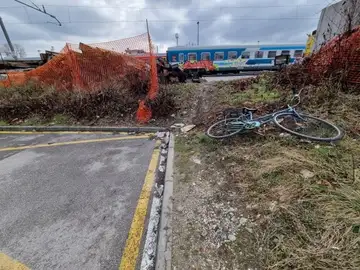 Kolo leži na travi pri parkirišču in gradbeni ograji