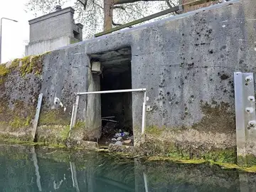 Majhen tunel ali odtočna odprtina z odpadki ob vodi
