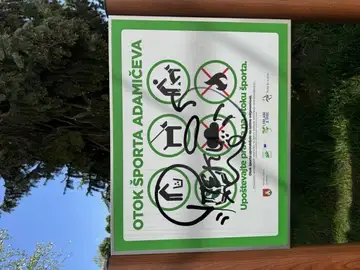 Vandaliziran znak s pravili športnega otoka z grafiti