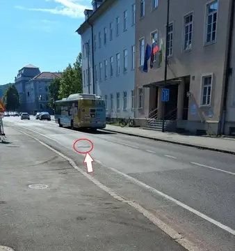 Avtobus na cesti z luknjo označeno z rdečim krogom in puščico