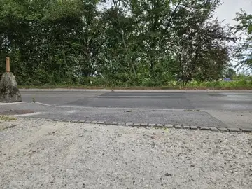 Neenakomerna površina ceste s popravki ob zaraščenem robu