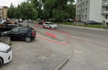 Poškodovana cestna površina pri parkiranih avtomobilih in stanovanjski stavbi