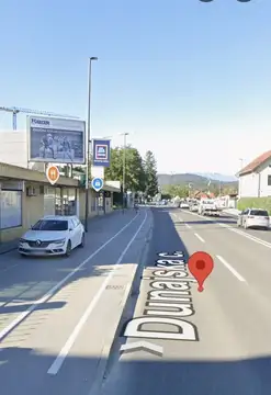 Ulica s parkiranimi avtomobili in označeno kolesarsko stezo na pločniku