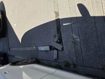 Poškodovani robniki na pločniku ob parkiranem avtu