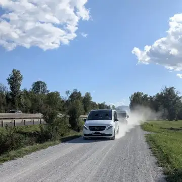 Dva kombija vozita po prašni makadamski cesti ob avtocesti