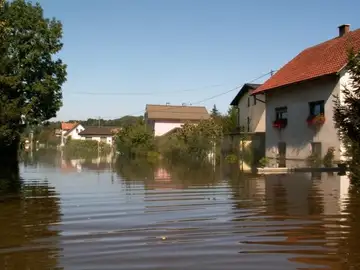 Poplavljena stanovanjska ulica z vodo na cesti in dvoriščih