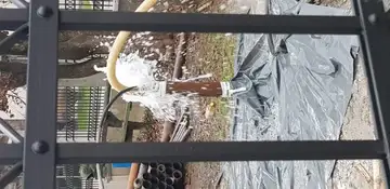 Počen vodovod pušča vodo za kovinsko ograjo