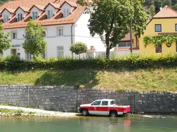 Poltovornjak delno potopljen v reki ob kamnitem nabrežju